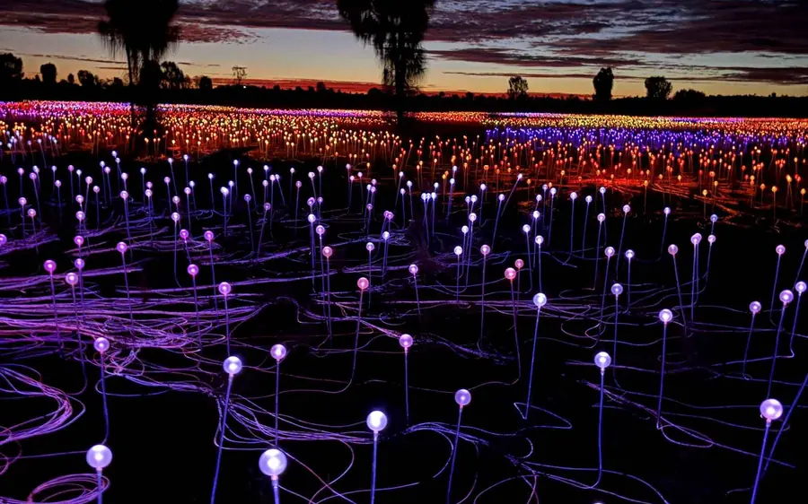 Rows of small glowing glass spheres spread across the desert floor at first light