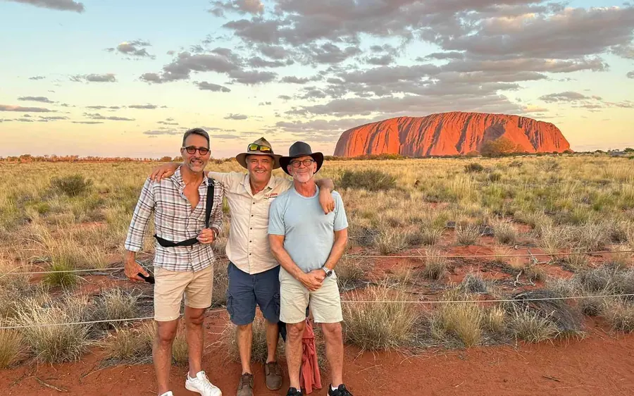 A guide showing ancient rock art on the wall of a cave at the base of Uluru
