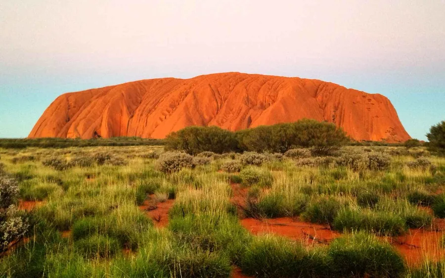 A guide with a small group of people on a path at the foot of Uluru