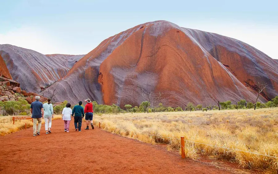 A walking track running along the base of Uluru with the red rock wall on one side