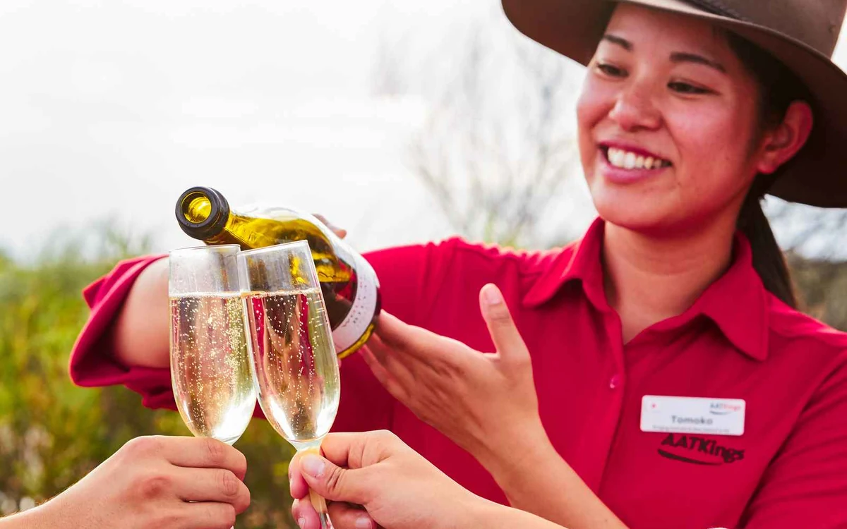 Glasses of sparkling wine on a table in the desert with Uluru in the low evening Light